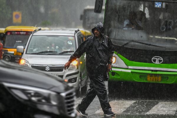 A pedestrian crosses a road amid a rainfall in New Delhi on May 1, 2023. - Sputnik India