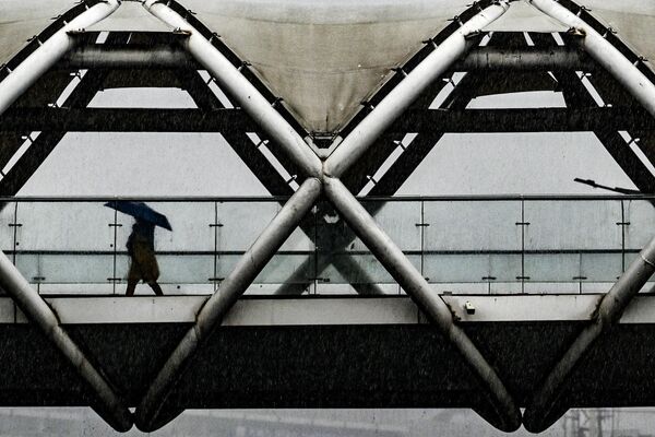 A woman holding an umbrella walk along an overbridge during a downpour in New Delhi on May 1, 2023. - Sputnik India