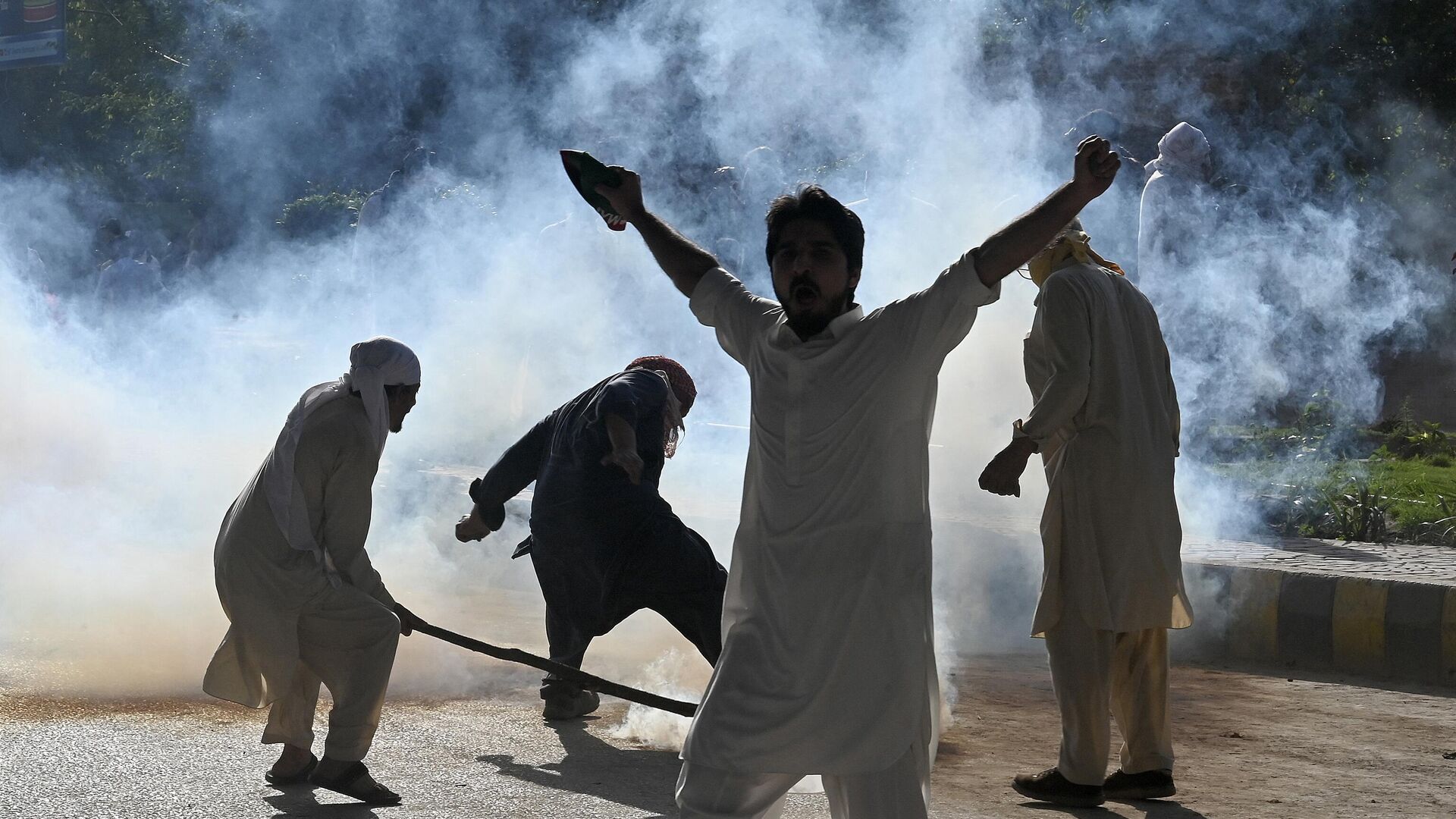 Pakistan Tehreek-e-Insaf (PTI) party activists and supporters of former Pakistan's Prime Minister Imran clash with police amid teargas during a protest against the arrest of their leader, in Peshawar on May 9, 2023. - Sputnik India, 1920, 17.05.2023