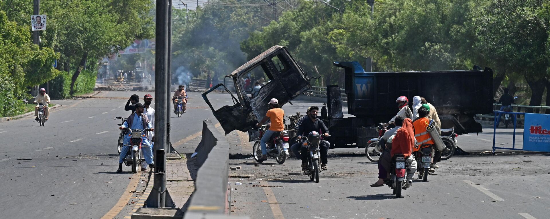 Motorists ride past burnt vehicles in front of the Zaman Park, a day after protests by Pakistan Tehreek-e-Insaf (PTI) party activists and supporters of former Pakistan's Prime Minister Imran Khan, in Lahore on May 10, 2023. - Sputnik India, 1920, 10.05.2023