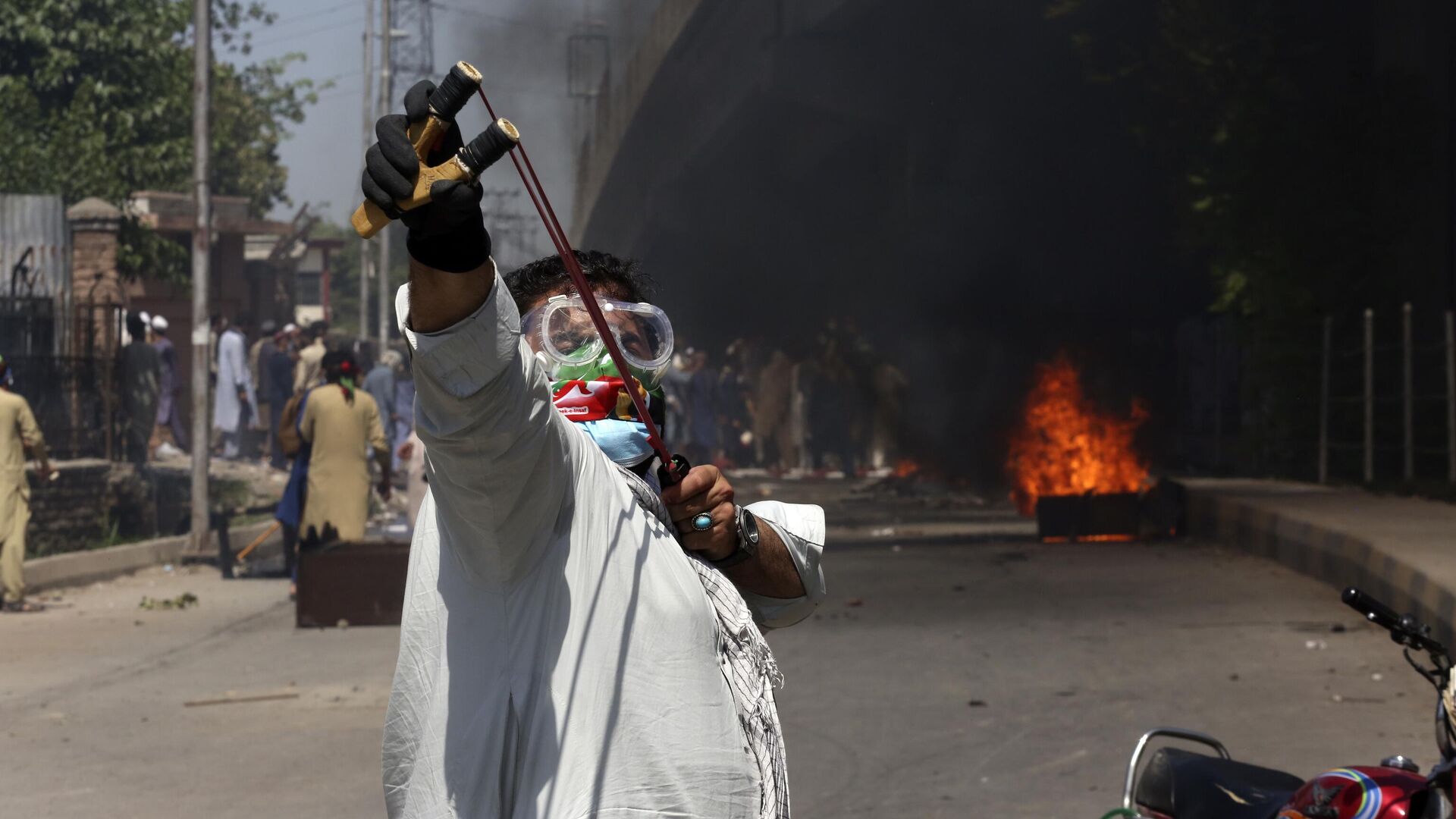A supporter of Pakistan's former Prime Minister Imran Khan throws stones using a slingshot toward police officers during a protest against the arrest of their leader in Peshawar, Pakistan, Wednesday, May 10, 2023. - Sputnik India, 1920, 14.05.2023
