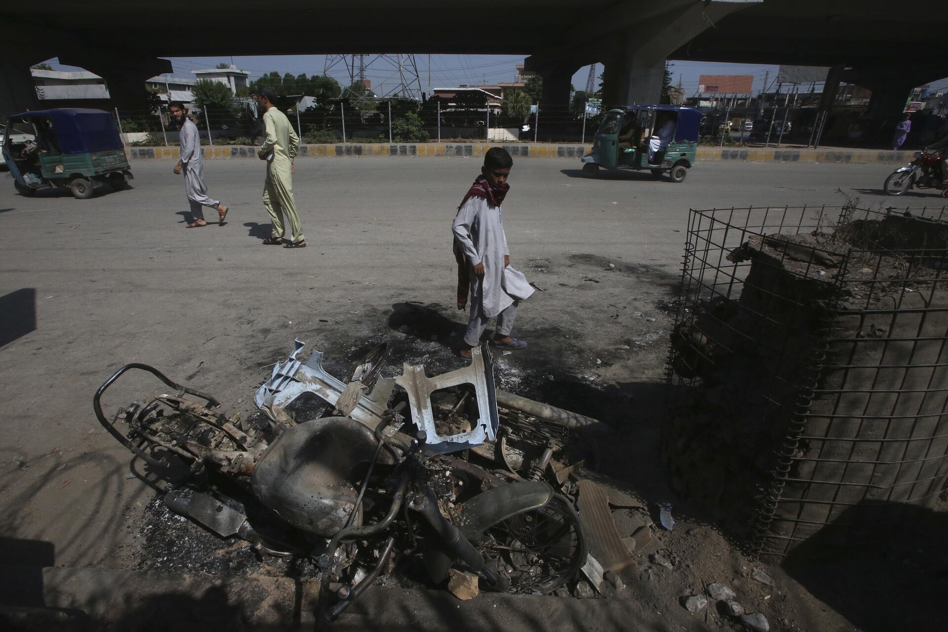 A boy looks at a burnt motorbike on a roadside a day after of violent protest by Pakistan's former Prime Minister Imran Khan supporters following his arrest, in Peshawar, Pakistan, Wednesday, May 10, 2023. - Sputnik India, 1920, 11.05.2023