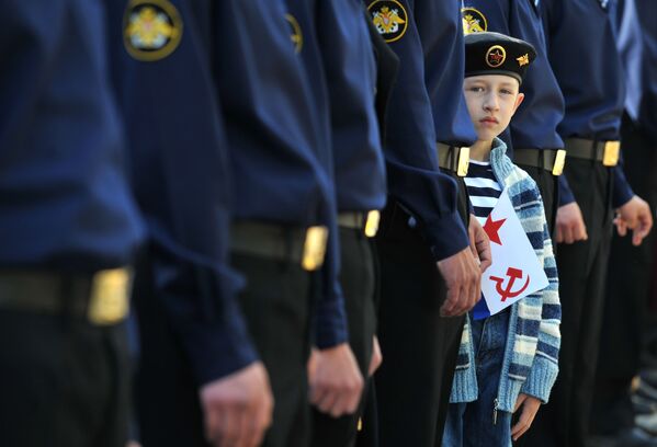 A boy holds a Soviet Navy flag as he looks out from a line of Russian seamen line up Sevastopol, the main base of the Russian Black Sea Fleet. - Sputnik भारत