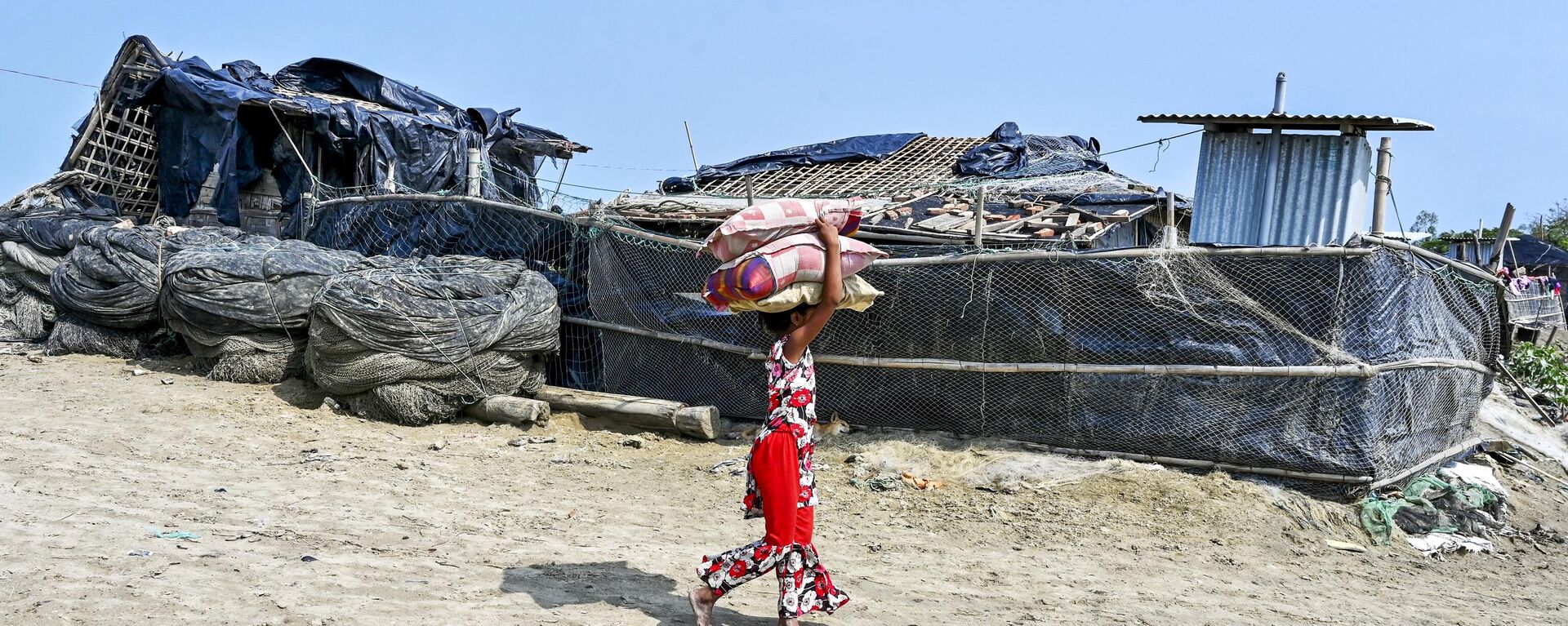 A girl carries belongings as she returns from a shelter in Shahpori island on the outskirts of Teknaf on May 15, 2023, a day after the cyclone Mocha's landfall. - Sputnik India, 1920, 15.05.2023