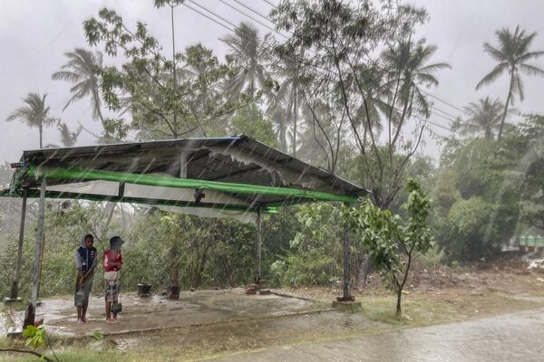 Двое детей стоят под навесом, чтобы защититься от дождя перед циклоном Мокко, Мьянма - Sputnik भारत