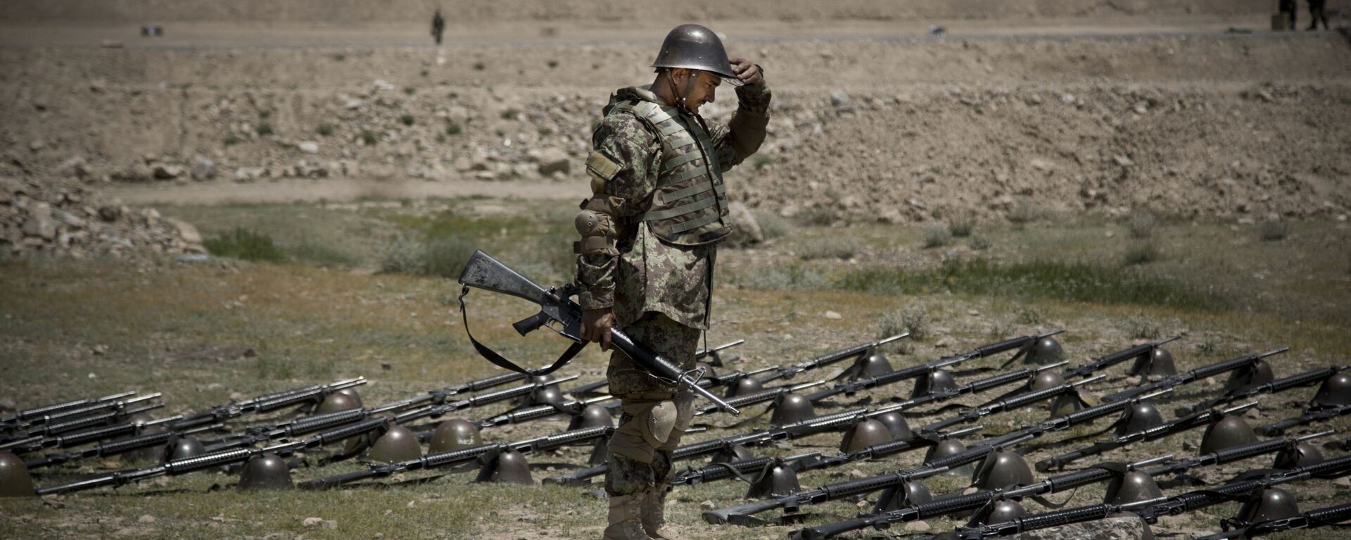 An Afghan Army soldier pauses before dropping his helmet and his gun next to his comrade's equipment at a training facility in the outskirts of Kabul, Afghanistan on Wednesday, May 8, 2013. - Sputnik India, 1920, 16.05.2023