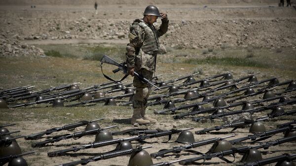 An Afghan Army soldier pauses before dropping his helmet and his gun next to his comrade's equipment at a training facility in the outskirts of Kabul, Afghanistan on Wednesday, May 8, 2013. - Sputnik India