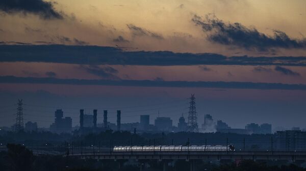 A Delhi Metro train runs in the background of chimneys from the defunct Indraprastha Thermal Power Plant Delhi in New Delhi, India - Sputnik India