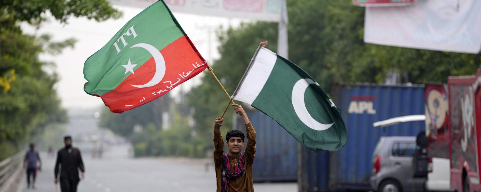 A supporter of Pakistan's former Prime Minister Imran Khan holds flags near his house, in Lahore, Pakistan, Wednesday, May 17, 2023. - Sputnik India, 1920, 18.05.2023