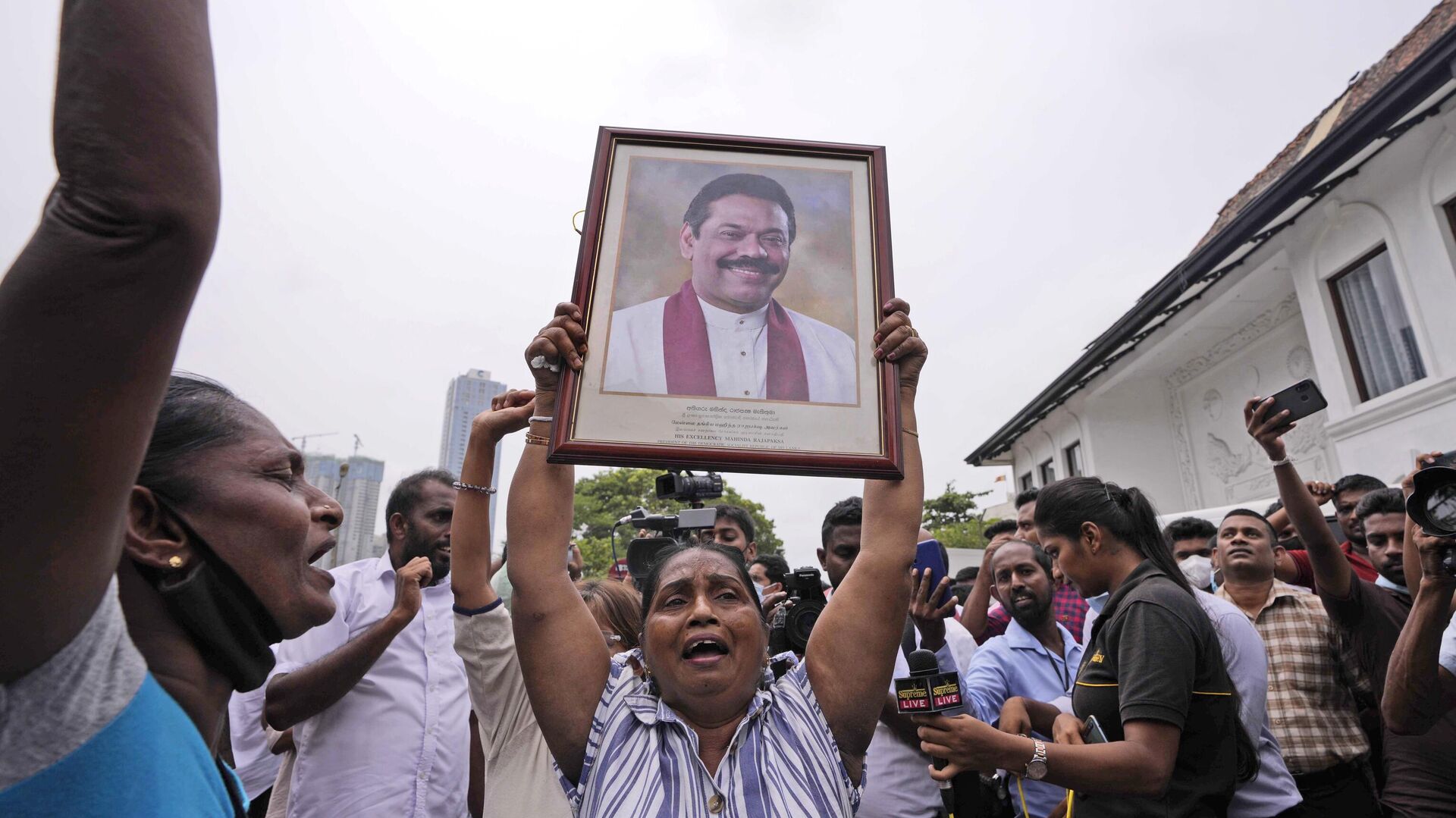 Sri Lankan government supporters shout slogans holding a portrait of prime minister Mahinda Rajapaksa outside his official residence in Colombo, Sri Lanka, Monday, May 9, 2022. - Sputnik India, 1920, 18.05.2023