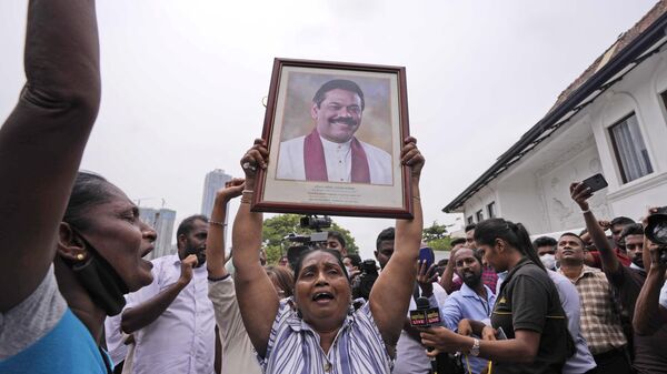 Sri Lankan government supporters shout slogans holding a portrait of prime minister Mahinda Rajapaksa outside his official residence in Colombo, Sri Lanka, Monday, May 9, 2022. - Sputnik India