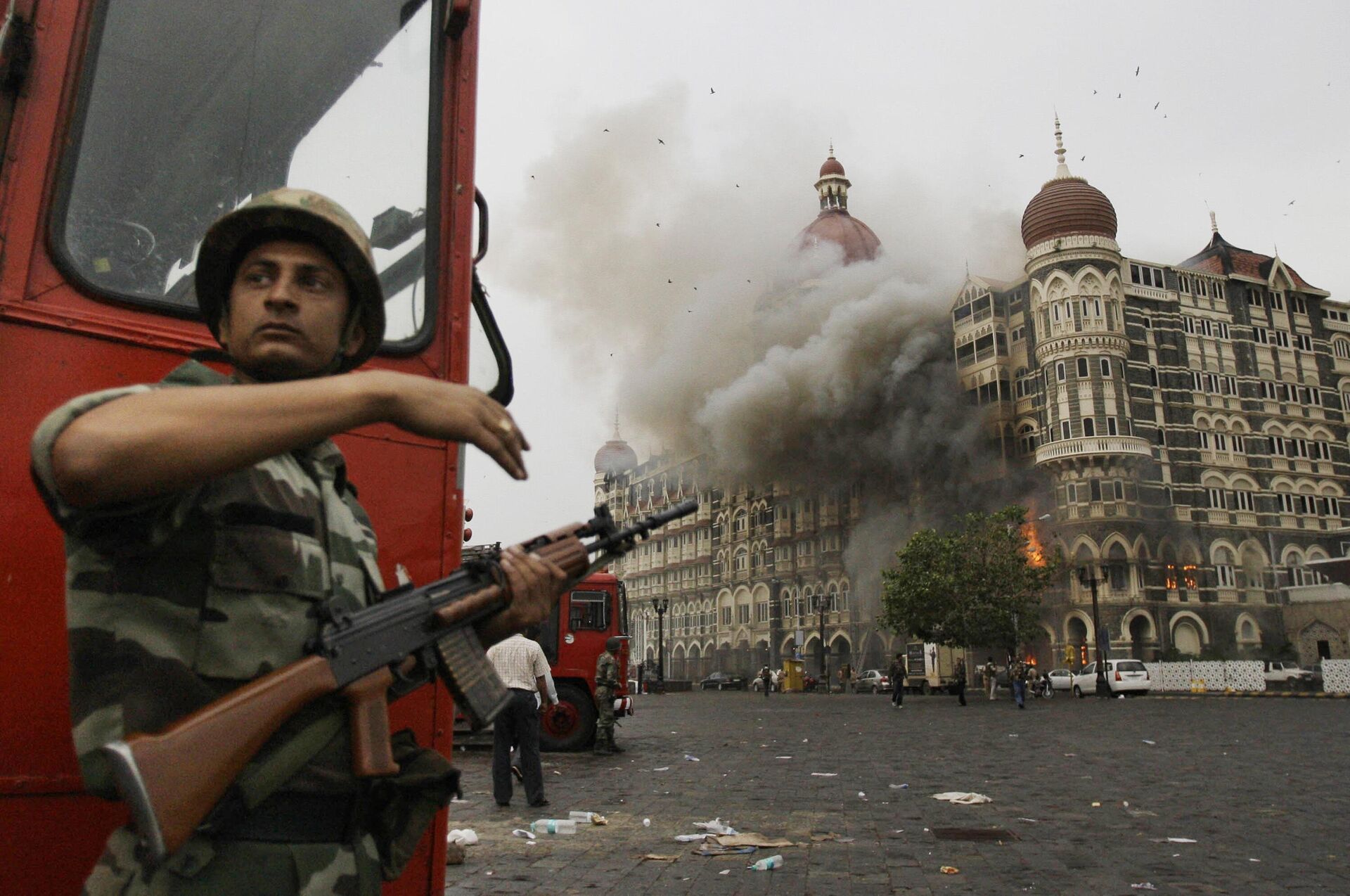An Indian soldier takes cover as the Taj Mahal hotel burns during gun battle between Indian military and militants inside the hotel in Mumbai, India, Nov. 29, 2008. - Sputnik भारत, 1920, 26.11.2023