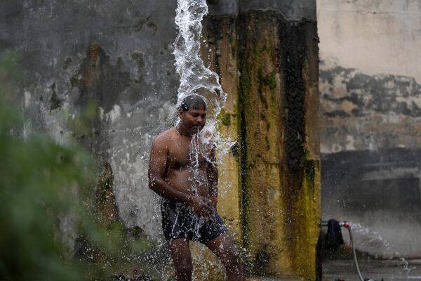 A man bathes from a roadside water tap to cool himself - Sputnik India