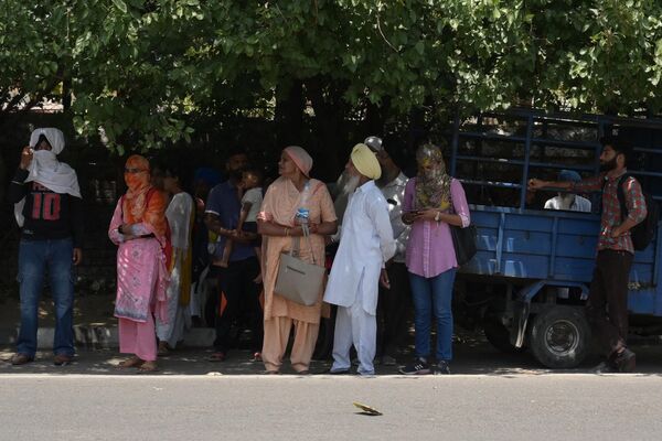 People wait for a bus under the shade of tree during a hot summer day - Sputnik India