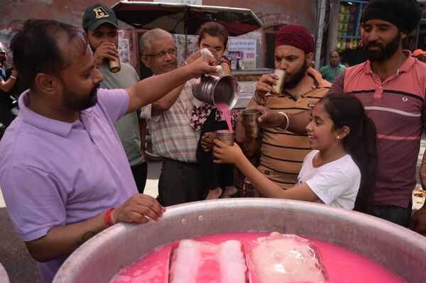 A volunteer distributes chilled sweet water to people during a hot summer day - Sputnik India