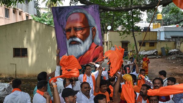 Bharatiya Janata Party (BJP) workers and activists carry a portrait of Indian Prime Minister Narendra Modi as they wait to see Modi during a road rally held by the BJP in Bengaluru on May 6, 2023, ahead of the Karnataka Assembly election. - Sputnik भारत