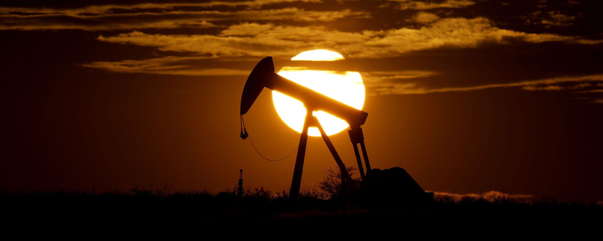 In this Wednesday, April 8, 2020, file photo, the sun sets behind an idle pump jack near Karnes City, Texas. Demand for oil continues to fall due to the new coronavirus outbreak. - Sputnik India, 1920, 27.03.2026