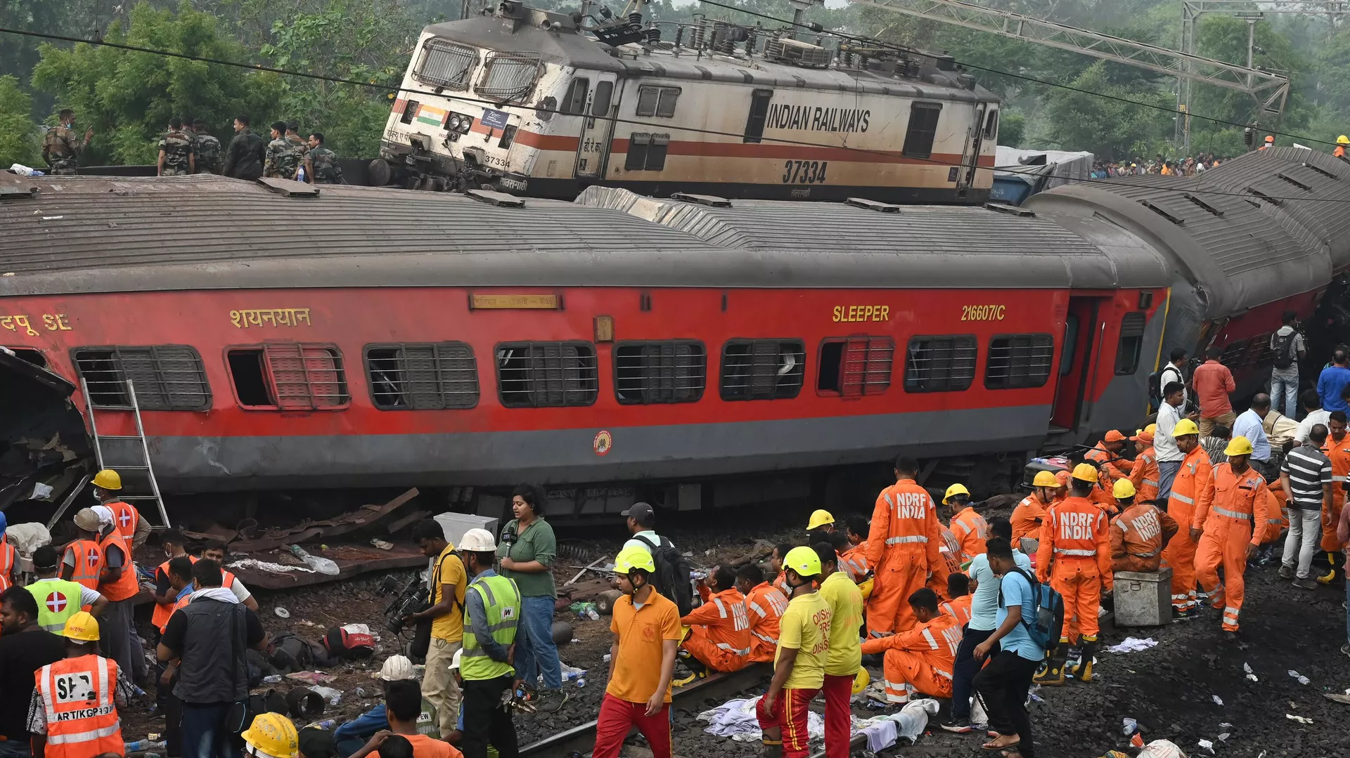 Rescue workers and military personnel gather around damaged carriages at the accident site of a three-train collision near Balasore, about 200 km (125 miles) from the state capital Bhubaneswar in the eastern state of Odisha, on June 3, 2023. At least 288 people were killed and more than 850 injured in a horrific three-train collision in India, officials said on June 3, the country's deadliest rail accident in more than 20 years. (Photo by DIBYANGSHU SARKAR / AFP)