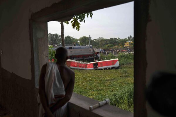 ट्रेन के पटरी से उतरने की जगह पर अपने घर की बालकनी से देखता एक शख्स। (AP Photo/Rafiq Maqbool) - Sputnik भारत