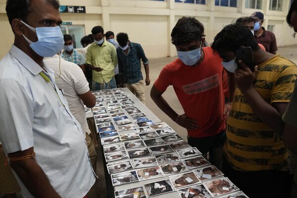 लोग उन लोगों की तस्वीरों को देख रहे हैं जिनकी पहचान की जा नहीं पाई। (AP Photo/Rafiq Maqbool) - Sputnik भारत
