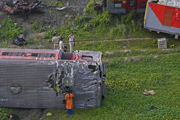 कुचली हुई बोगियों का निरीक्षण करते एक पुलिसकर्मी। (Photo by DIBYANGSHU SARKAR / AFP) - Sputnik भारत