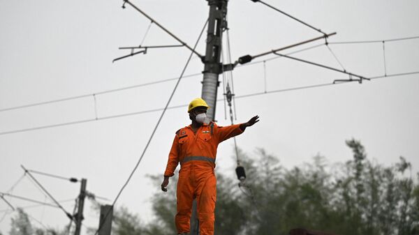 A railway worker stands on the roof of a service carriage to restore overhead electrical supply wires at the accident site of a three-train collision near Balasore, about 200 km (125 miles) from the state capital Bhubaneswar in the eastern state of Odisha, on June 4, 2023. - Sputnik India