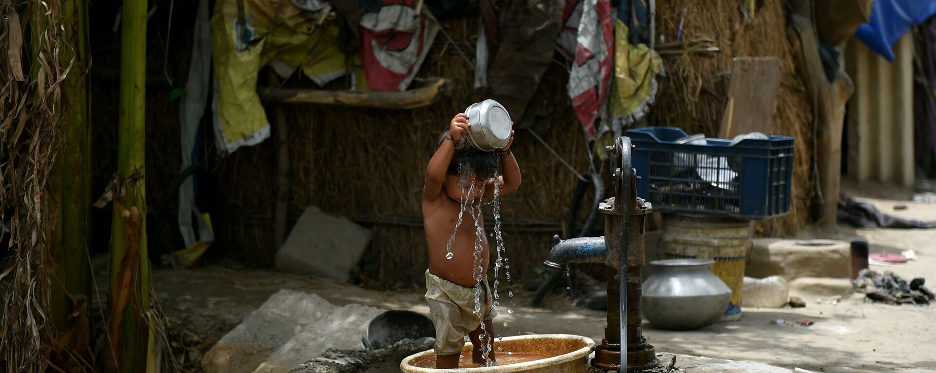 A young Indian child pours water on himself as he attempts to cool himself off in New Delhi on May 28, 2015. More than 1,100 people have died in a blistering heatwave sweeping India, authorities said, as forecasters warned searing temperatures would continue.  - Sputnik India, 1920, 12.06.2023