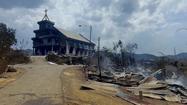 The remains of a burnt church (L) and houses (R) are seen in Langching village some 45 km from Imphal on May 31, 2023, during ongoing ethnic violence in India's northeastern Manipur state. - Sputnik भारत