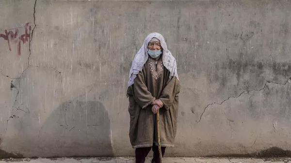An elderly Kashmiri woman watches as India's opposition Congress party leader Rahul Gandhi and other leaders walk during a 5-month-long Unite India March, in Srinagar, Indian controlled Kashmir, Sunday, Jan. 29, 2023. - Sputnik India