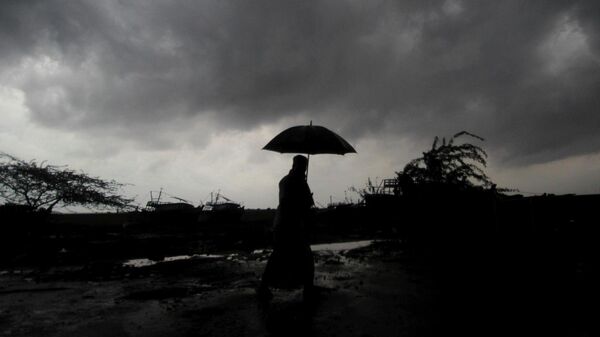 FILE - A villager holds an umbrella as dark clouds loom over Balasore district in Odisha, India - Sputnik India