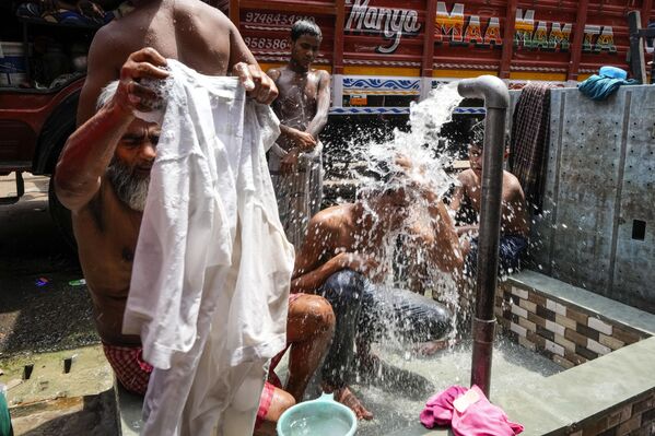 A daily wage laborer takes bath to beat the heat while other washes his clothes from a roadside municipal tap in Kolkata, India, Friday, June 16, 2023. - Sputnik India