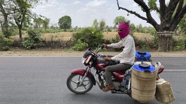 A milkman rides his motorcycle has his containers covered with wet jute sacks to prevent the milk from getting damaged due to excess heat in Lalitpur,  Uttar Pradesh state, India, Saturday, June 17, 2023. - Sputnik India