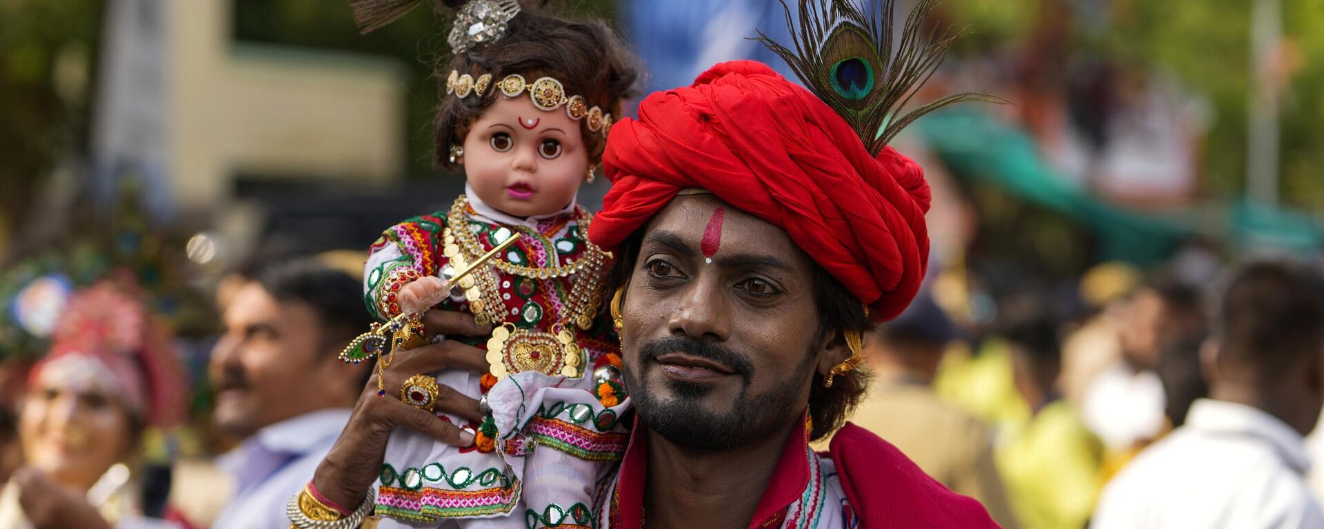 A man walks carrying a doll dressed as a Hindu deity during the annual chariot festival of Hindu god Lord Jagannath in Ahmedabad, India, Tuesday, June 20, 2023. - Sputnik India, 1920, 20.06.2023