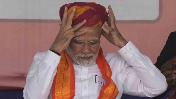 Indian Prime Minister Narendra Modi removes a turban presented to him during a public meeting ahead of the upcoming Gujarat state assembly elections in Mehsana, India, Wednesday, Nov. 23, 2022. - Sputnik India