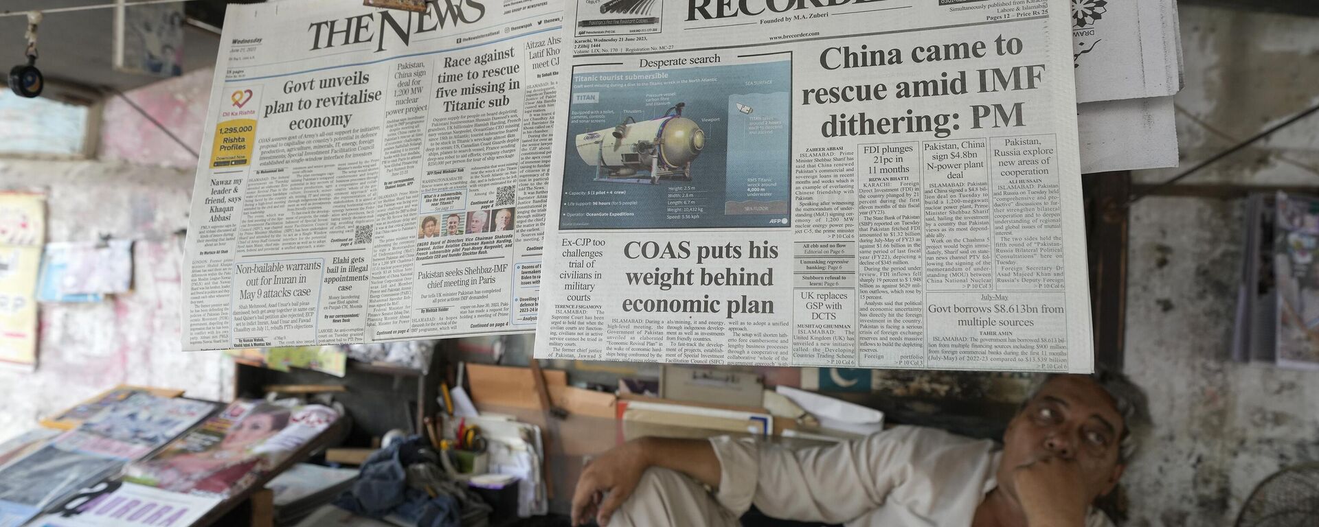 A vendor sits beside a copy of a morning newspaper which reports missing Titanic submersible and onboard five people, including Pakistani nationals Shahzada Dawood and his son Suleman, at a stall, in Karachi, Pakistan, Wednesday, June 21, 2023. - Sputnik India, 1920, 21.06.2023