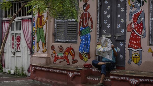 A man reads newspaper on the stairs of a building decorated with wall paintings in Kolkata, India, Sunday, July 17, 2022. - Sputnik India