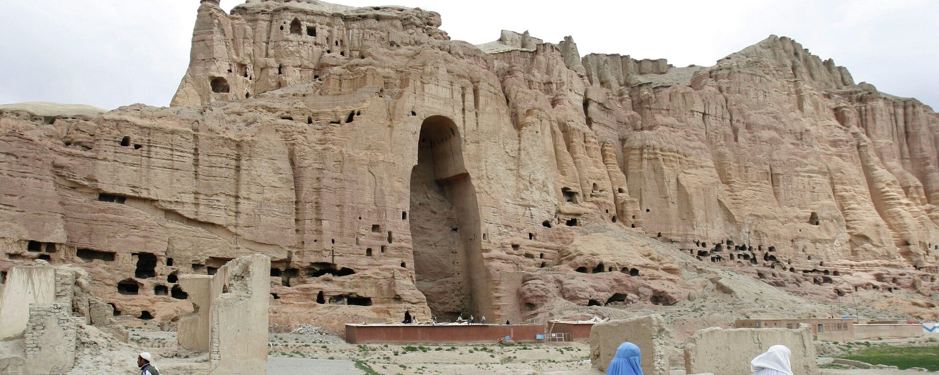 FILE - In this June 17, 2009 file photo, two women walk past the cliffs that once held giant Buddhas destroyed by the Taliban in 2001 in Bamiyan, central Afghanistan - Sputnik India, 1920, 23.06.2023