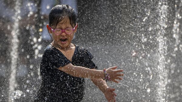 A girl reacts as she plays in a fountain at a shopping mall in Beijing, Friday, June 23, 2023. - Sputnik India