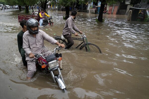 पाकिस्तान में लाहौर में भारी बारिश के कारण जलमग्न सड़क से चलते हुए मोटरसाइकिल चालक, सोमवार, जून 26, 2023. (AP Photo/K.M. Chaudary) - Sputnik भारत