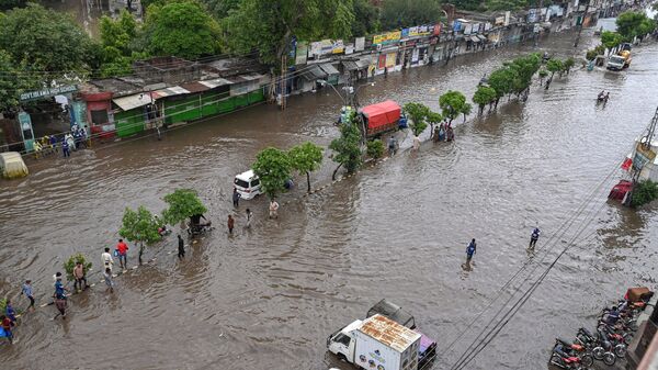 Люди идут по затопленной дороге из-за проливных дождей в Лахоре, Пакистан - Sputnik India