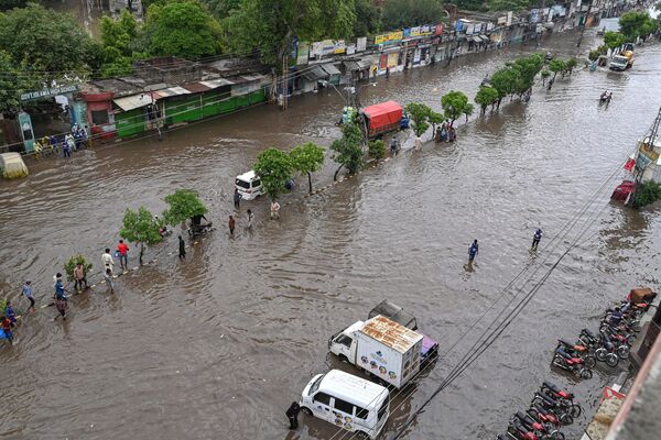 लाहौर में भारी बारिश के बाद लोग जलमग्न सड़क पर चल रहे हैं, जून 26, 2023. (Photo by Arif ALI / AFP) - Sputnik भारत