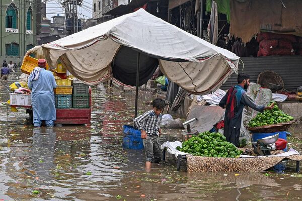 लाहौर में भारी बारिश के बाद लड़का पानी से भरे बाज़ार से गुज़र रहा है, जून 26, 2023. (Photo by Arif ALI / AFP) - Sputnik भारत