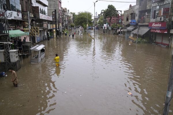 पाकिस्तान में लाहौर में भारी बारिश के कारण जलमग्न सड़क से गुजरते लोग, सोमवार, जून 26, 2023. (AP Photo/K.M. Chaudary) - Sputnik भारत