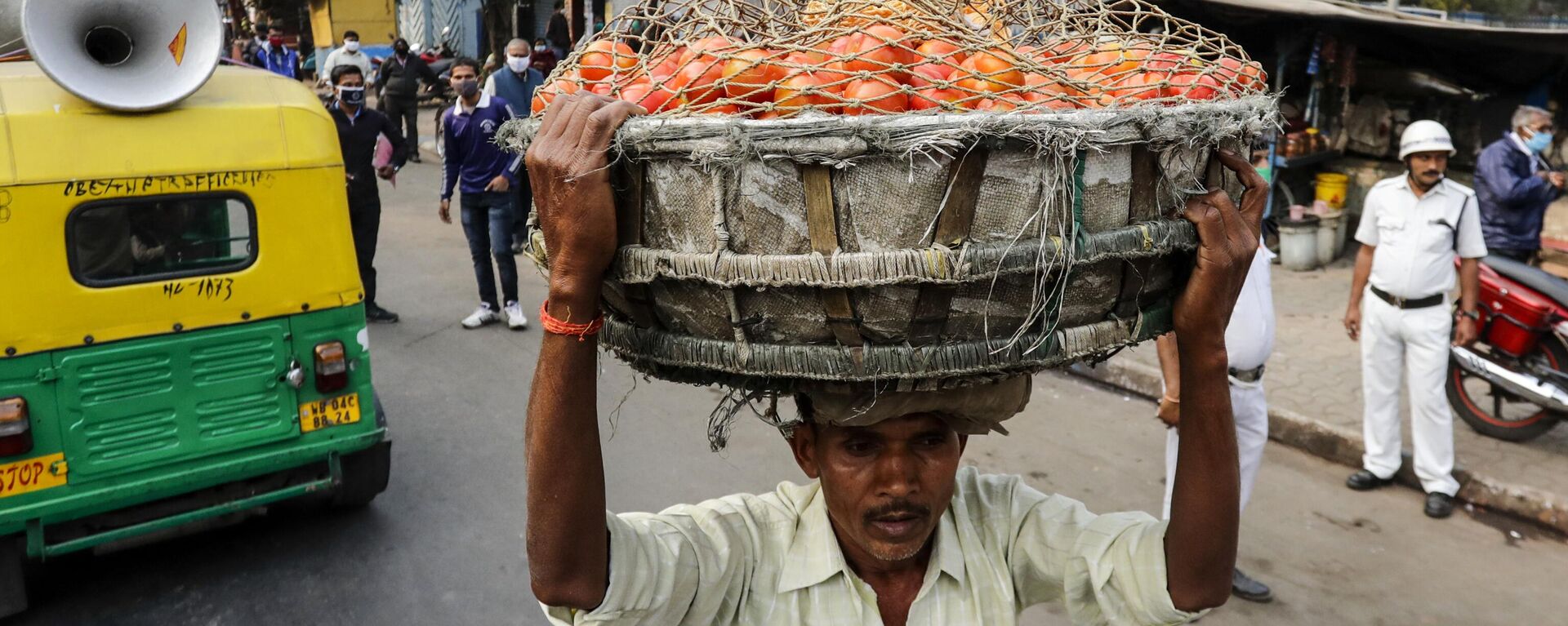 A man carries a basket on his head filled with tomatoes to be delivered to a nearby market in Kolkata, India, Saturday, Jan. 30, 2021. - Sputnik India, 1920, 28.06.2023