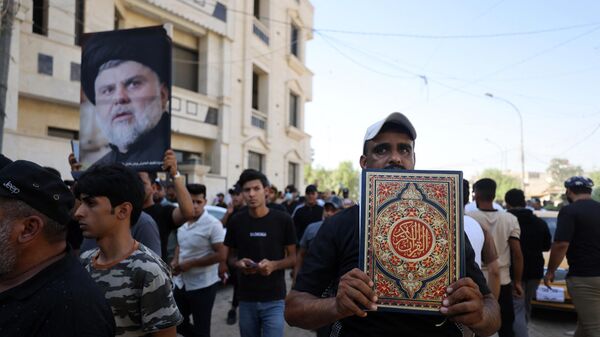 Сторонник Моктады Садра поднимает фотографию лидера мусульман-шиитов, в то время как другой несет Коран, во время демонстрации у посольства Швеции в Багдаде - Sputnik भारत