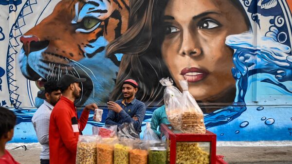 Торговец возле настенной росписи, созданной в рамках творческого сотрудничества между Индией и посольством Нидерландов, Нью-Дели, Индия - Sputnik भारत