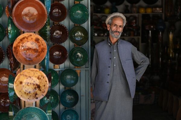 मिट्टी के कटोरे बेचने वाली अपनी दुकान में एक अफ़ग़ान विक्रेता ग्राहकों का इंतज़ार कर रहा है। (Photo by Wakil Kohsar / AFP) - Sputnik भारत