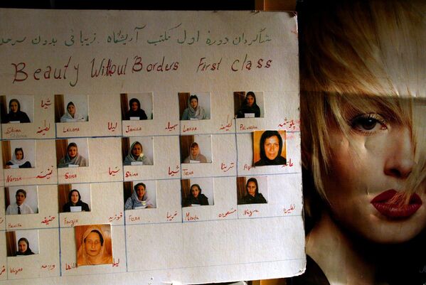 काबुल ब्यूटी स्कूल की पहली कक्षा की स्नातक महिलाओं की तस्वीरों वाला एक पोस्टर (AP Photo/Elizabeth Dalziel) - Sputnik भारत
