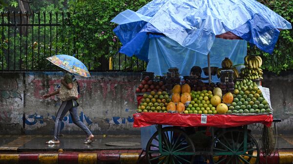 A vendor waits for customers as it rains in New Delhi on July 8, 2023. - Sputnik भारत