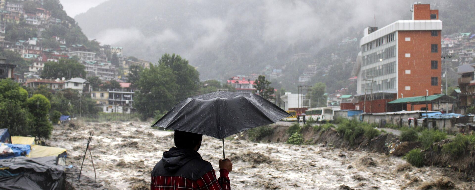 A man looks at a swollen River Beas following heavy rains in Kullu, Himachal Pradesh, India, Sunday, July 9, 2023. According to local reports heavy rain fall has triggered landslides, damaged houses and caused loss of lives. - Sputnik India, 1920, 16.08.2023
